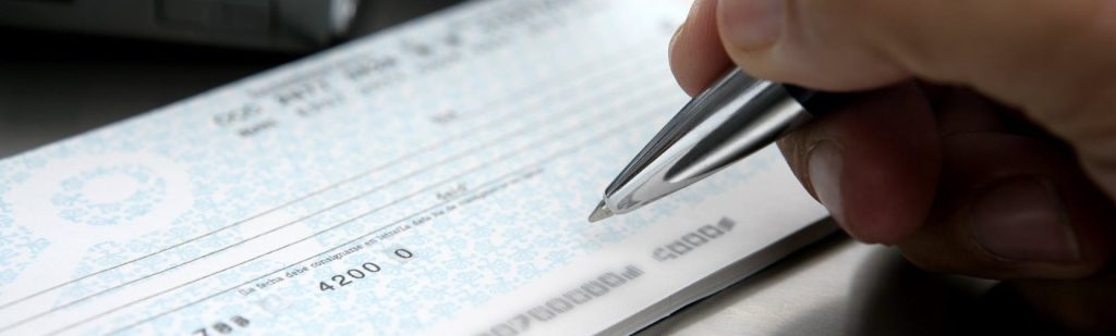Close-up of a hand signing a cheque, representing financial fraud and fraudulent misrepresentation claims in Ontario and BC