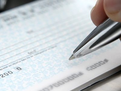 Close-up of a hand signing a cheque, representing financial fraud and fraudulent misrepresentation claims in Ontario and BC